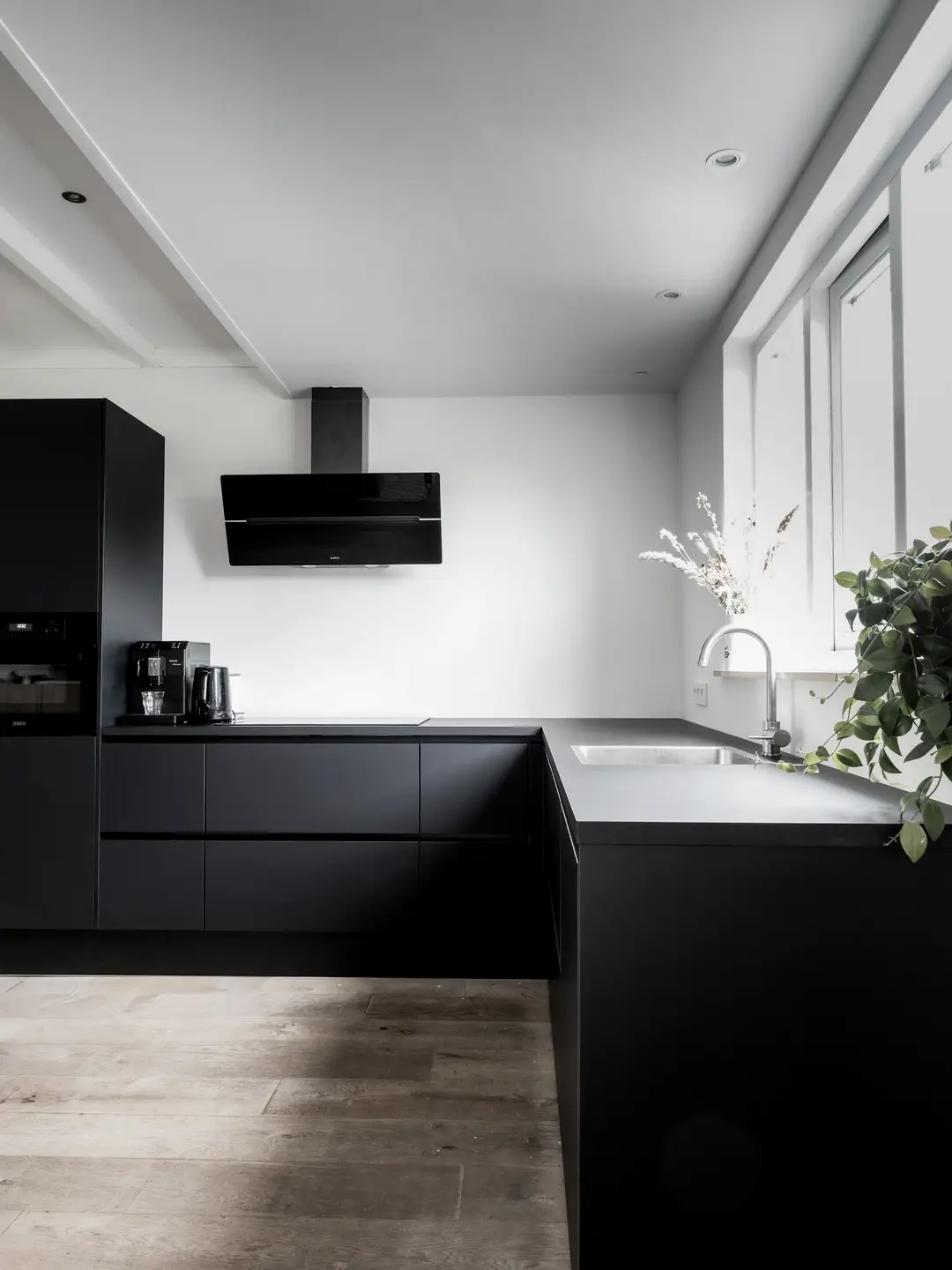Cuisine aux armoires noires mates sans poignées et plancher de bois