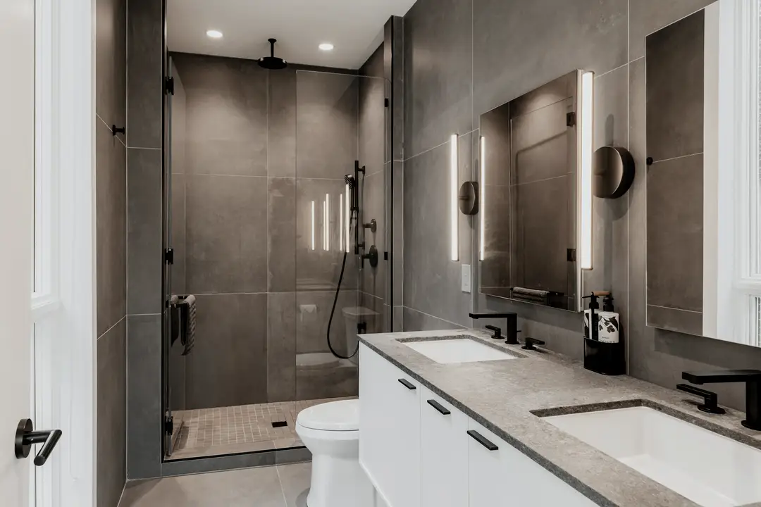 Salle de bain avec douche vitrée, grands carreaux et double meuble-lavabo éclairé
